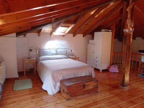 a bedroom with a large bed and a wooden floor at Amplia y cómoda casa de piedra con porche y jardín in San Roque de Ríomiera