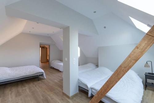 Duas camas num quarto com paredes brancas e pisos em madeira em CABANA & La Villa sur la Colline - Au Calme 