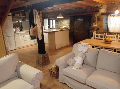 a living room with two white couches and a kitchen at Amplia y cómoda casa de piedra con porche y jardín in San Roque de Ríomiera