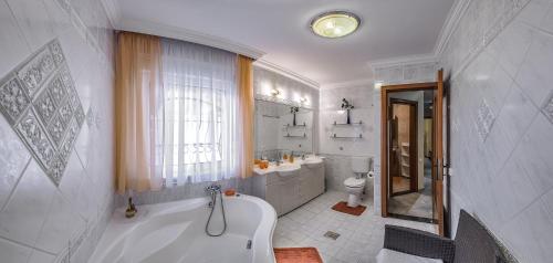a white bathroom with a tub and a sink at Fortuna Villa in Hévíz