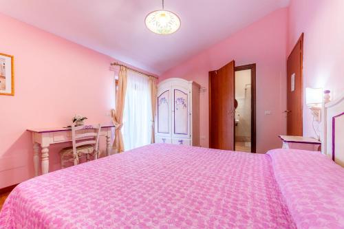 a pink bedroom with a large bed and a desk at B&B Capriccio in Rocca Priora