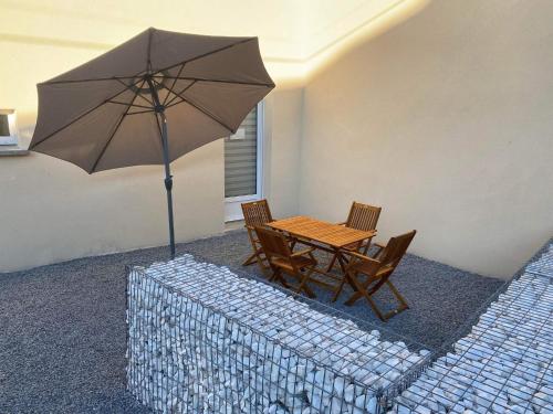 uma mesa e cadeiras com um guarda-sol num quarto em Maison rénovée au calme em Dannevoux