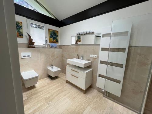 uma casa de banho com 2 lavatórios, um chuveiro e um WC. em Gemütliches Haus zwischen Förde und Golfplatz em Heikendorf