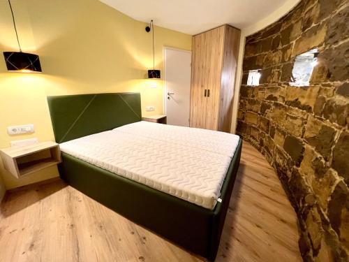 a bed in a room with a stone wall at Casa Histria Apartments in Šmarje