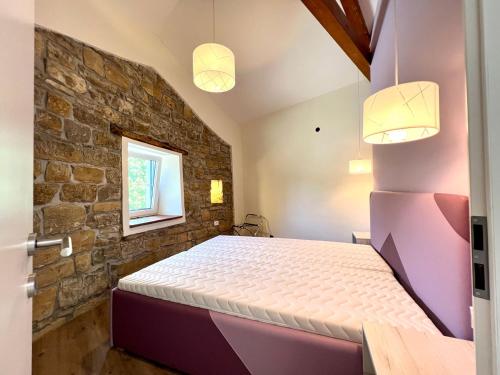 a bedroom with a bed and a brick wall at Casa Histria Apartments in Šmarje