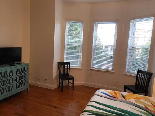 a bedroom with a bed and two chairs and a television at Reservoir Hill Mansion - 4 bedrooms in Baltimore