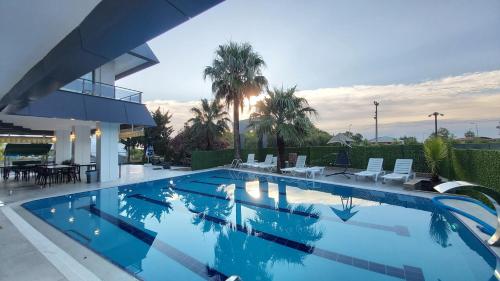 a swimming pool with chairs and a house at PALMİLA BUTİK OTEL in Silifke