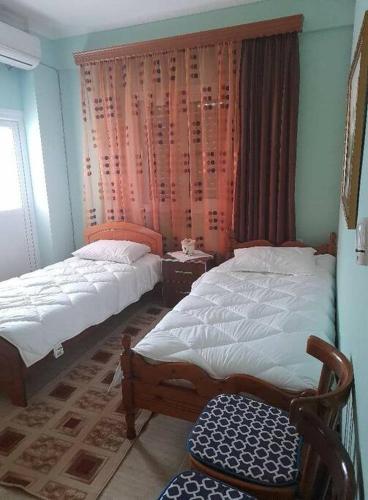 a bedroom with two beds and a chair and a window at Chrisa apartament in Metogjashta