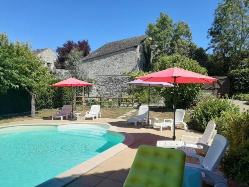 a swimming pool with lawn chairs and umbrellas at Au Chat Perché chambre double in Mareil-sur-Mauldre