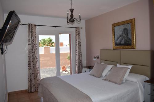 a bedroom with a bed and a sliding glass door at Villa Experience Heated Salty Water Pool in Caleta De Fuste