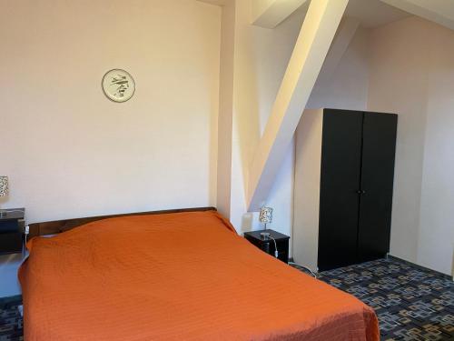a bedroom with a orange bed and a black cabinet at Valentina's Rooms in Vilnius
