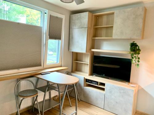 uma pequena cozinha com uma mesa e uma televisão e uma janela em Pole Mokotowskie Apartament em Varsóvia