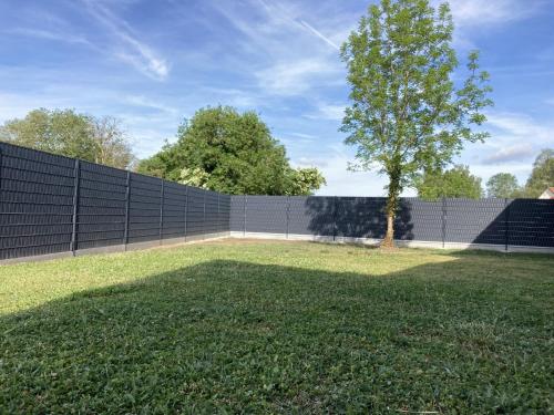 a fence with a tree in the middle of a yard at Domaine du lion rouge Piscine et Spa in Coucy-le-Château-Auffrique