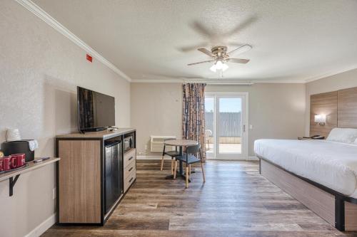 a bedroom with a bed and a television and a table at Harbor House Inn in Morro Bay