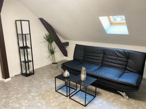 a black leather couch in a living room with a table at Cozy Apartment Bernburg 3 in Roschwitz