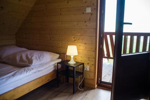 a bedroom with a bed and a lamp on a table at 2 Domki w Górach in Łącko