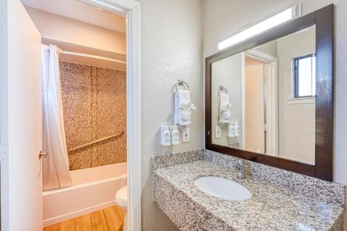 a bathroom with a sink and a toilet and a mirror at Harbor House Inn in Morro Bay