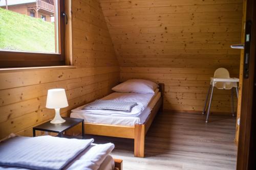 two beds in a wooden room with a window at 2 Domki w Górach in Łącko
