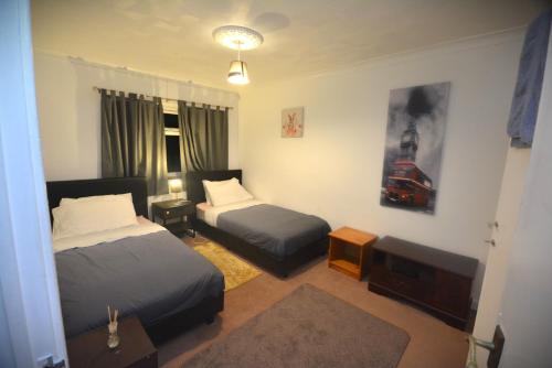 a hotel room with two beds and a table at Spacious 3 bedroom House in Tilbury by London in Low Street