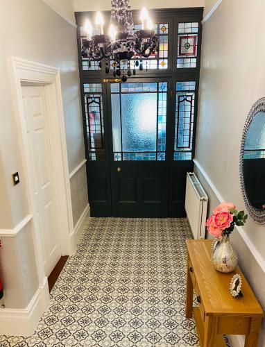 a hallway with a black door and a vase with flowers at All Seasons Bed & Breakfast - Adults Only in Weston-super-Mare