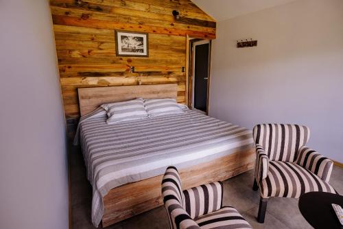 a bedroom with a bed and two chairs at Cabañas Valle de los Ciervos in Tandil