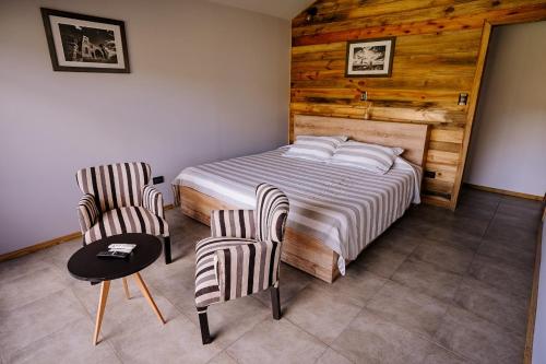 a bedroom with a bed and two chairs and a table at Cabañas Valle de los Ciervos in Tandil