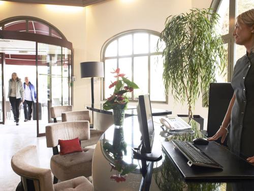 a woman standing in front of a desk with a computer at Golf Hôtel in Brides-les-Bains