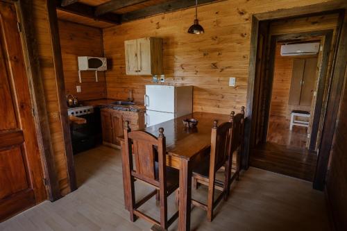 a kitchen with a table and a white refrigerator at Cabañas Valle de los Ciervos in Tandil
