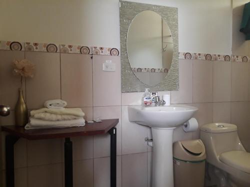 y baño con lavabo, espejo y aseo. en El Cardenal Hotel, en Loja