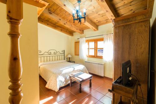 1 dormitorio con 1 cama y TV. en Casa Rural La Yedra, en Galve