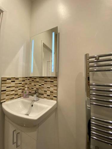 a white bathroom with a sink and a mirror at Comfortably furnished 2 bedroom home in Bolton in Bolton