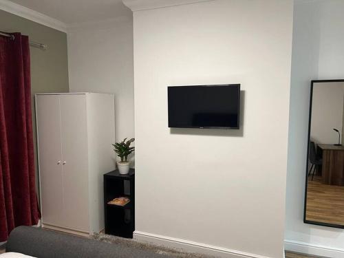 a room with a white wall with a flat screen tv at Comfortably furnished 2 bedroom home in Bolton in Bolton