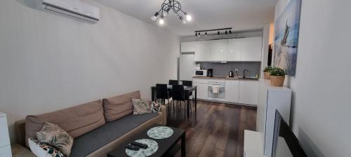 a living room with a couch and a kitchen at Green Apartments Kraków in Kraków