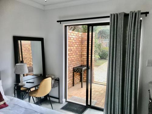 a bedroom with a bed and a desk and a sliding glass door at URRR Casa on Msasa in Randburg