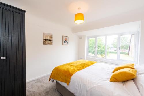 a bedroom with a bed with yellow pillows and a window at Fabulously presented 3 / 4 bedroom home in Woolton