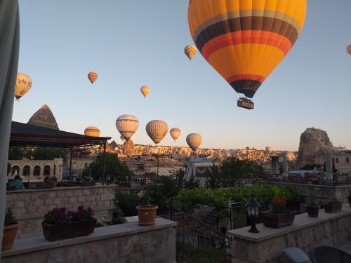 un grupo de globos de aire caliente volando sobre la ciudad en Guzide Cave Hotel en Goreme