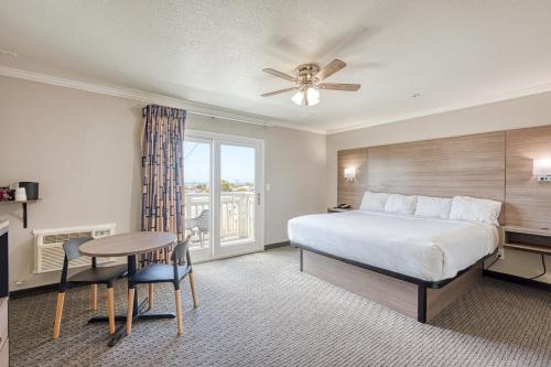 a bedroom with a bed and a table and a window at Harbor House Inn in Morro Bay