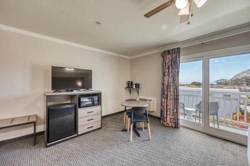 a hotel room with a bed and a television and a table at Harbor House Inn in Morro Bay