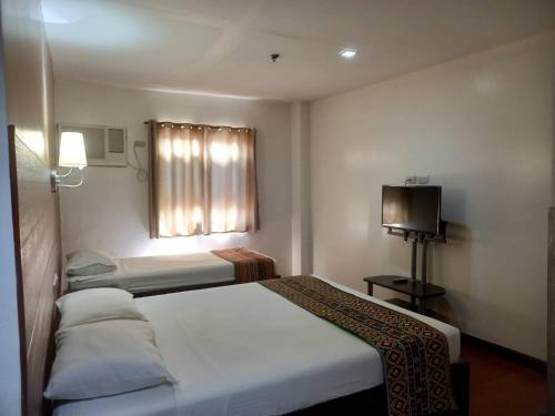 a hotel room with two beds and a television at W Hotel in Zamboanga