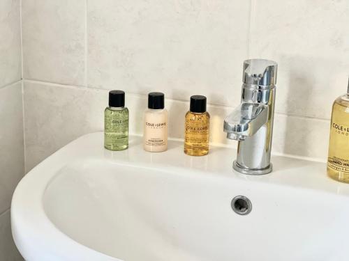 a bathroom sink with four bottles of soap on it at The Lambourne in Birstall