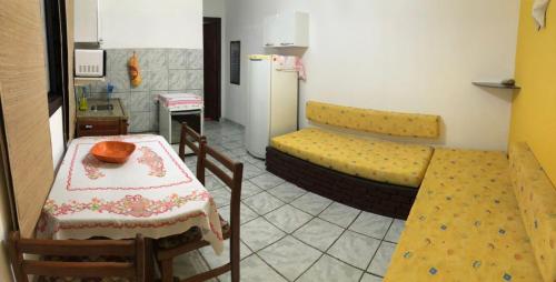 a room with a table and a couch and a kitchen at Chalés Alencar in Caraguatatuba