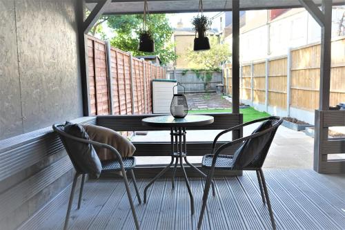 a patio with a table and chairs on a porch at Devonshire house-3.3ml from Wimbledon centre court in London