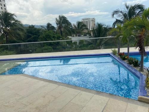 a swimming pool in a resort with palm trees at Magnifico apartamento con vista y salida al mar in Santa Marta