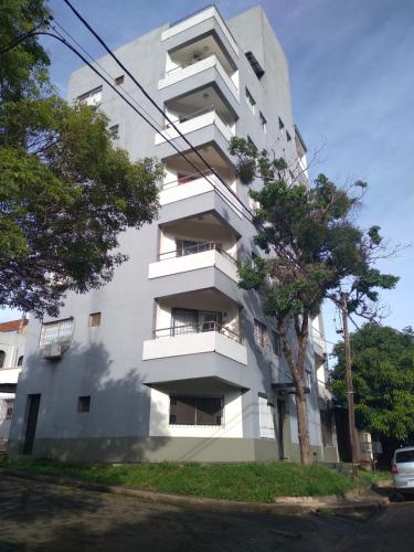 a white building with a tree in front of it at Departamento Augusta in Posadas