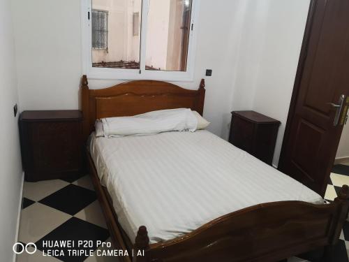 una camera da letto con un letto con lenzuola bianche e una finestra di Daya Rentals a Asilah