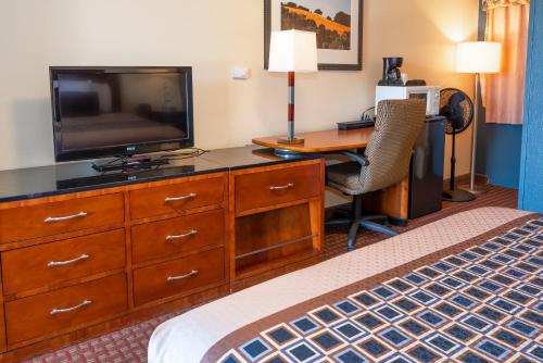 a hotel room with a bed and a desk with a television at Riviera Inn in Port Angeles