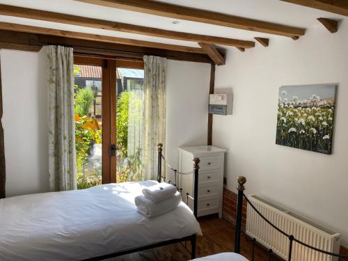 - une chambre avec un lit et une grande fenêtre dans l'établissement Brundish Suffolk Barn 2 Bed Idyllic 6 acres, à Wilby