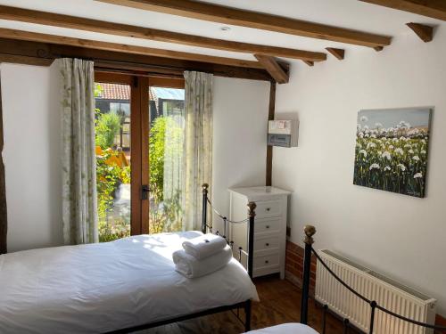 a bedroom with a bed and a large window at Brundish Suffolk Barn 2 Bed Idyllic 6 acres in Wilby