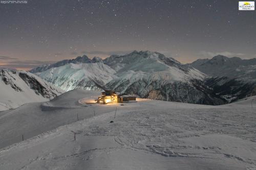 una cabaña en una montaña nevada por la noche en Wallackhaus RegioJet Hotels en Heiligenblut