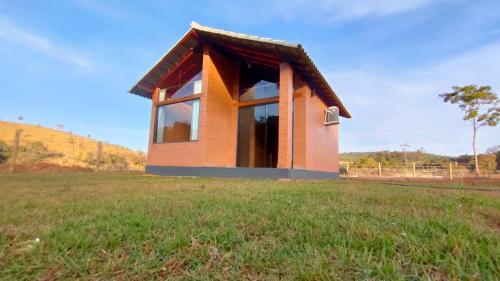 una pequeña casa con una ventana en un campo en Chalés Estância Campestre, en Capitólio